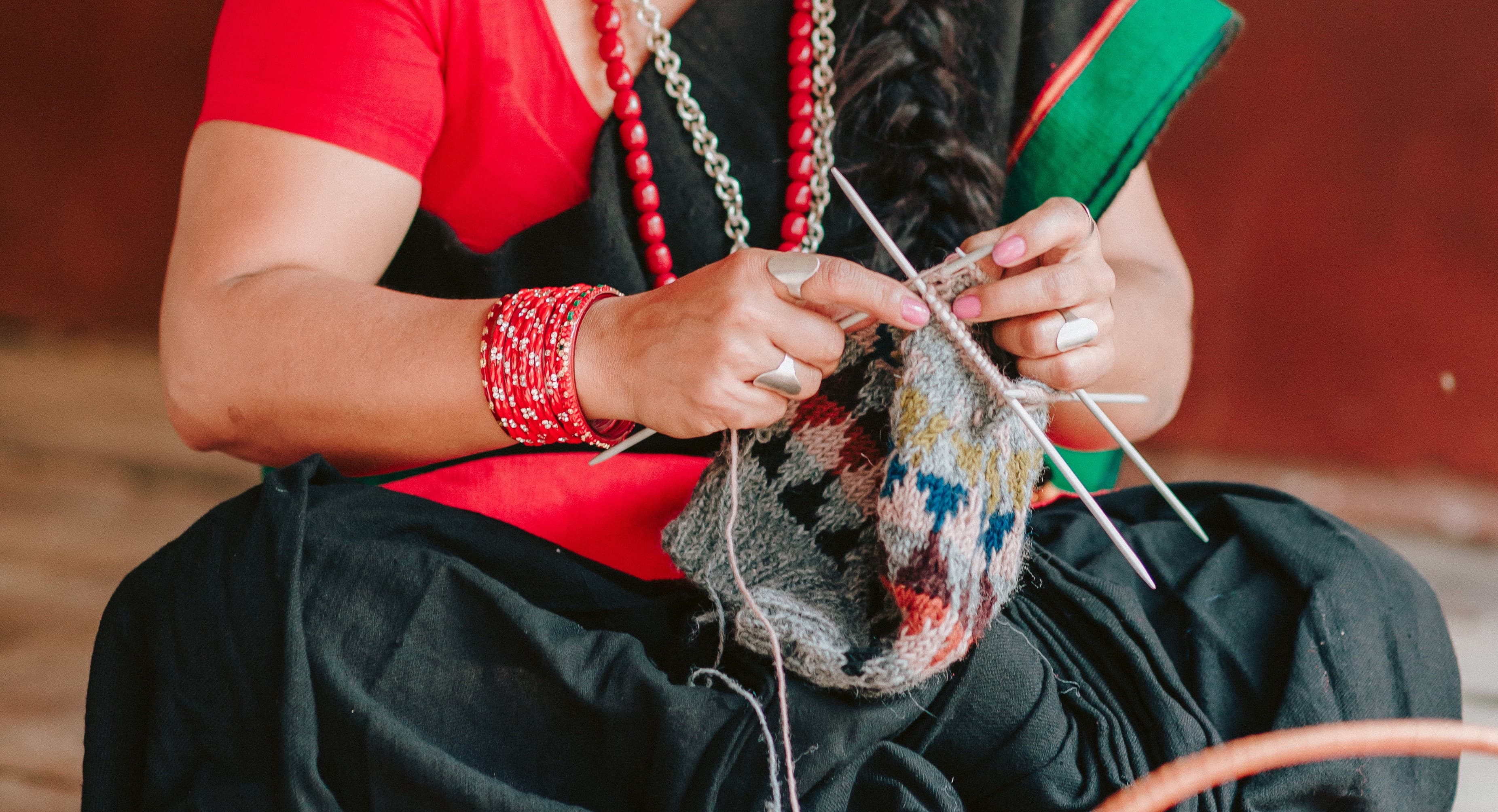 Close up of hands knitting with beige wool yarn in natural sunlight