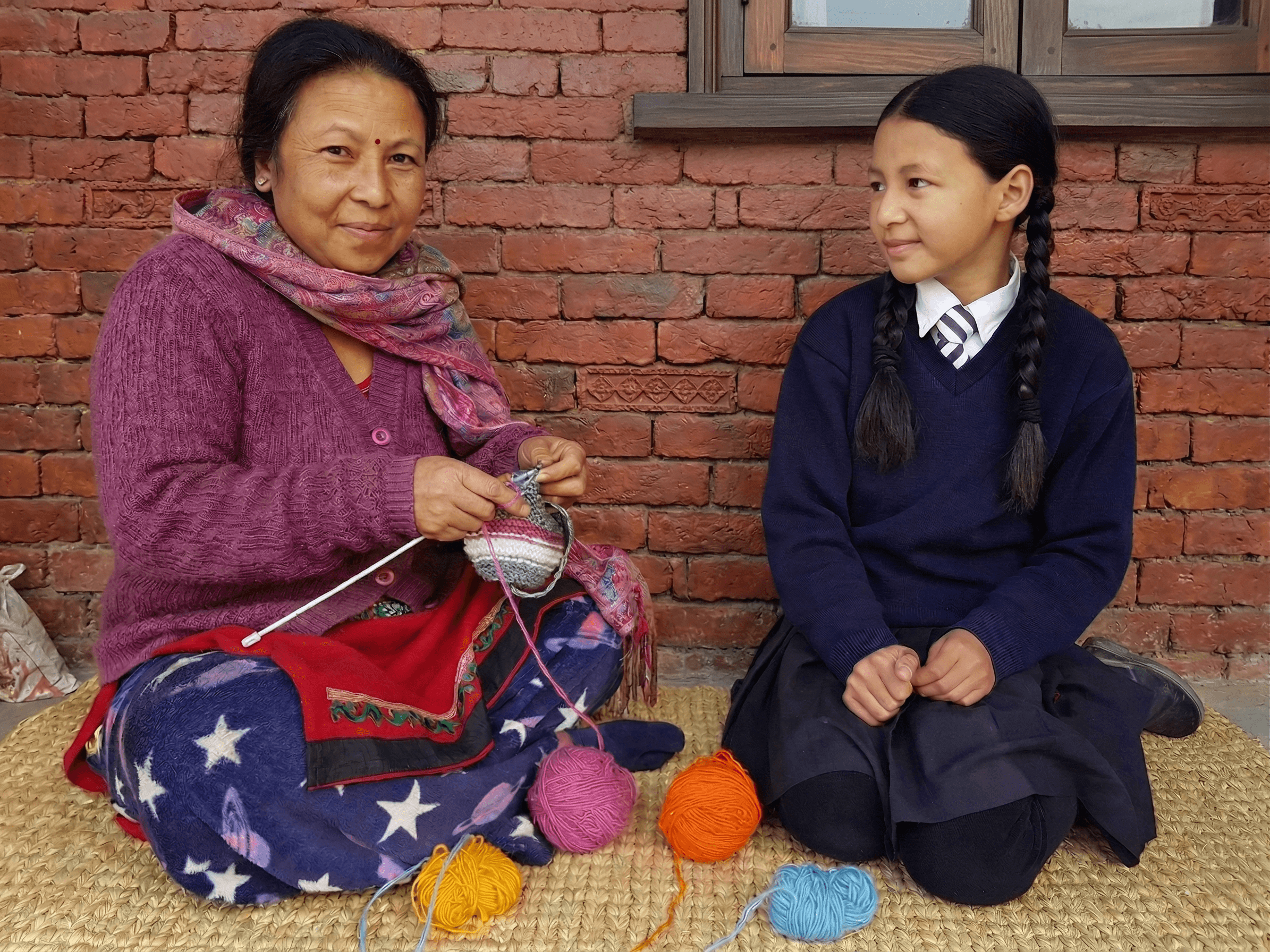 Portrait of Sarita Maharjan, Lead Artisan, knitting with daughter